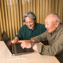 older adult and caregiver looking up on a laptop