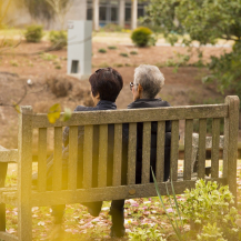 older adult and caregiver on a bench