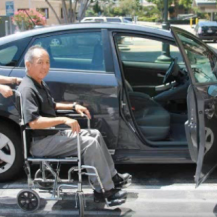 older adult in wheelchair getting transferred into car