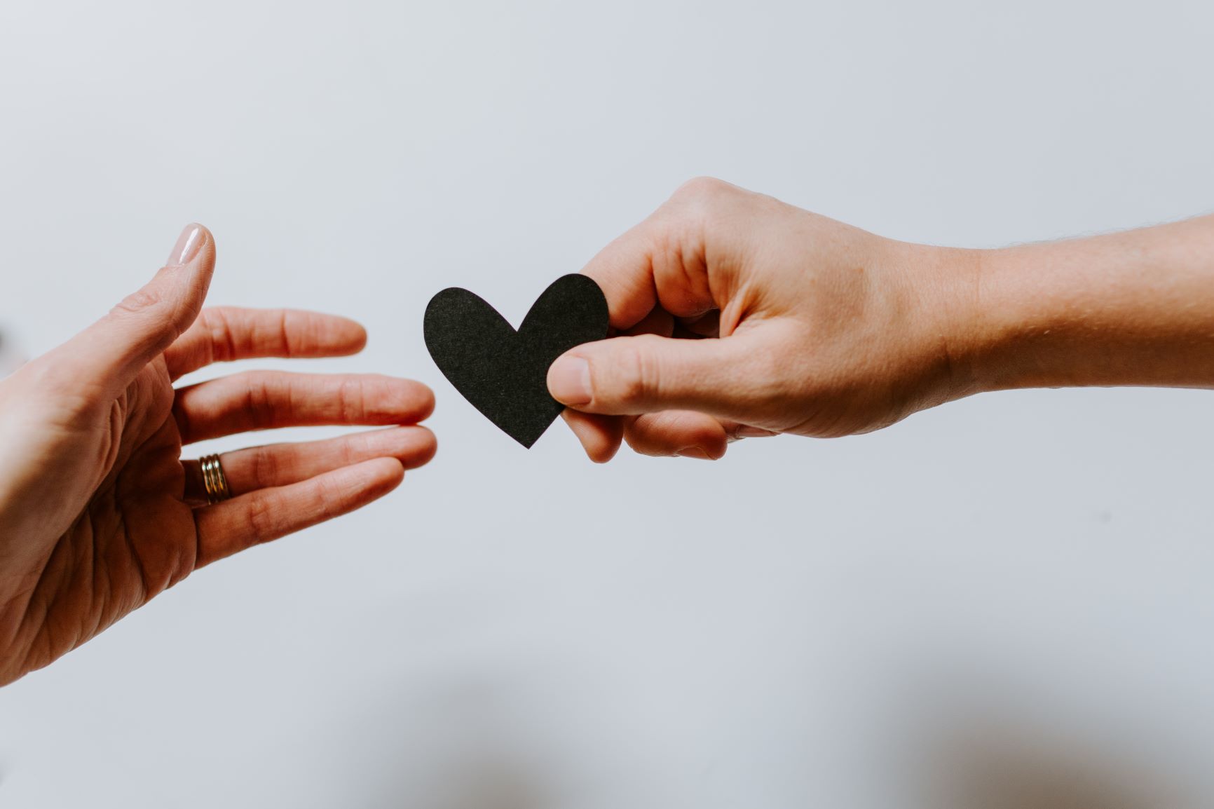 handing a paper heart to another hand