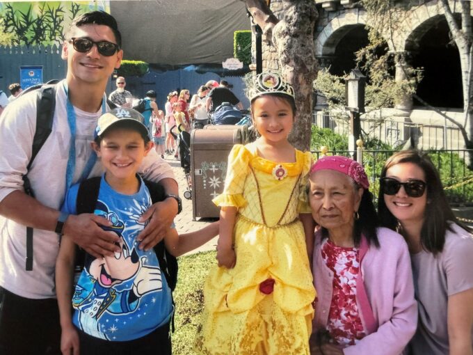 man in white shirt, boy in blue shirt, girl in yellow dress, older woman in pink, and woman with sunglasses