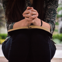 girl with journal on her lap clasping her hands