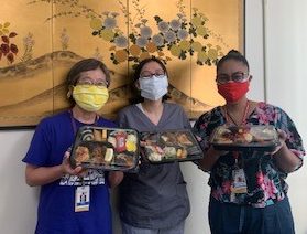 three people holding bento