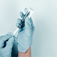 two hands wearing gloves holding a vaccine