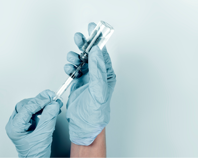 two hands wearing gloves holding a vaccine