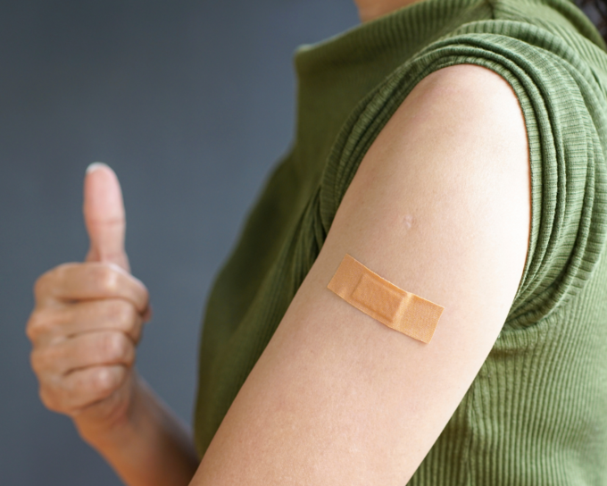 person with band aid on upper arm with thumbs up